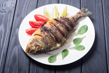 Fried fish dorado with lime , tomatoes and spinach