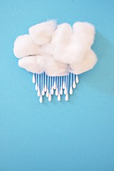 Cotton ball as a wool and earsticks as rain or snow on a blue background - concept for rain or fast with cotton swabs and cotton balls