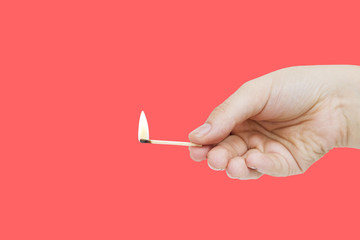 burning match in hand on red backgroound. Hand holding matchstick