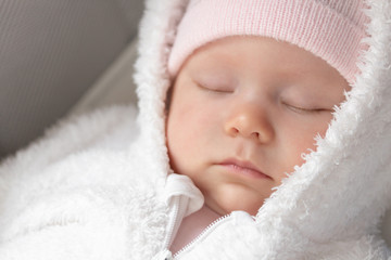 portrait of a sleeping newborn dressed in a warm fur suit and hat. sleeping little baby girl close-up.