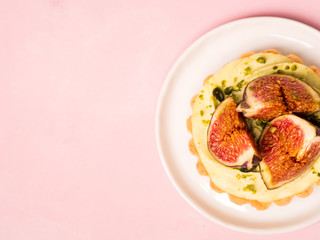 Delicious tart with fresh figs and pistachios on pink pastel backgrounds