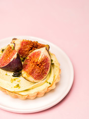 Delicious tart with fresh figs and pistachios on pink pastel backgrounds