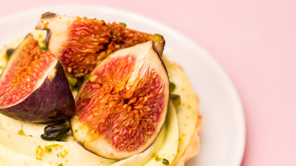 Delicious tart with fresh figs and pistachios on pink pastel backgrounds