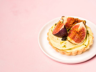 Delicious tart with fresh figs and pistachios on pink pastel backgrounds