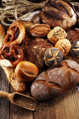 Different kinds of bread and bread rolls on board from above. Kitchen or bakery