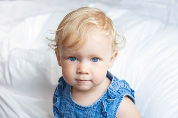 portret curly-haired blue-eyed little baby girl in jeans clothes