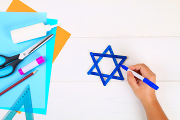 DIY. Star of David with his hands from ice cream sticks on a white wooden table.