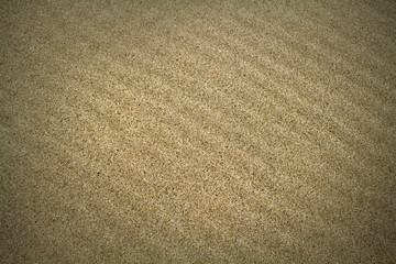 The background image of natural sea sand lies beautiful furrows. Background sand with vignetting.