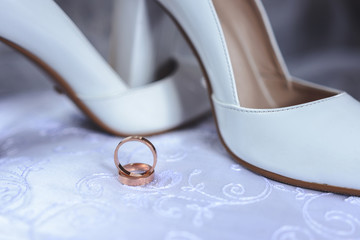 Beautiful wedding ring on the bride's white shoes