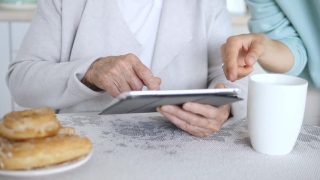 Hands Of Grandmother And Granddaughter Using Tablet Computer