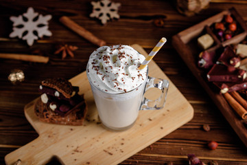 Hot chocolate drink with whipped cream. Cozy Christmas composition on a dark wooden background. Sweet treats for cold winter days.
