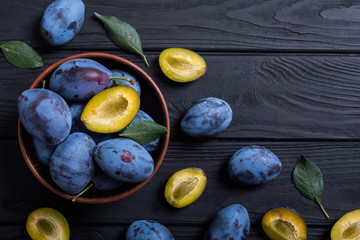 Fresh plums in bowl on wooden table