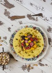 Vegan raw cheesecake with mango, black currant, blueberry, orange,  cashew cream, coconut butter and coconut milk, and base made of almonds, dates  and  dried apricots, oat flakes, lyophilisated berry