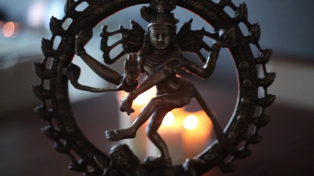 A figurine of shiva and candles on a wooden table