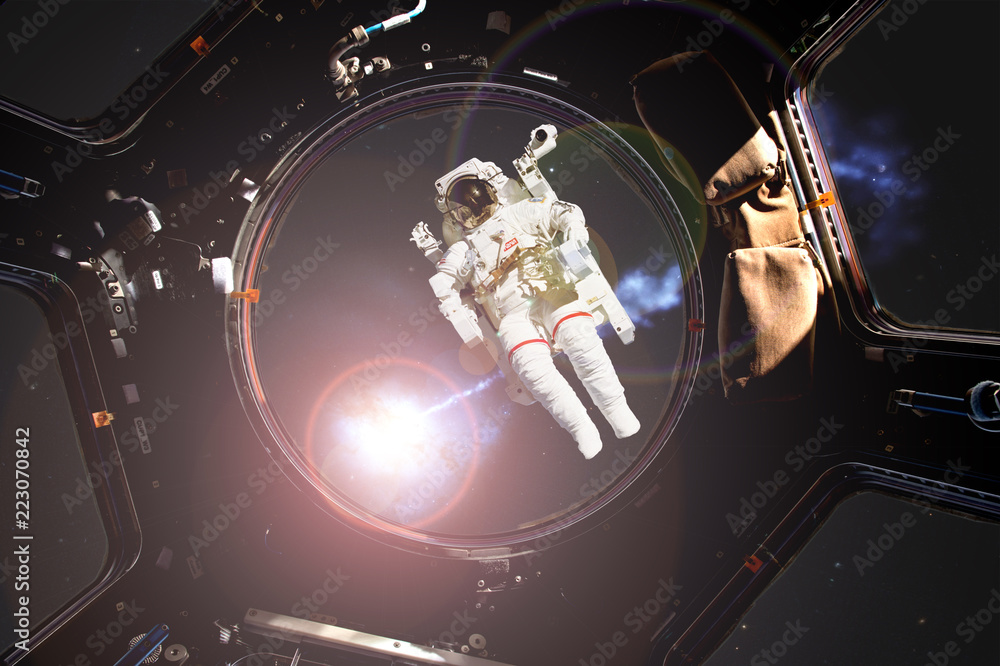 Wall mural view through the space ship illuminator of astronaut in open spacce with flare frome the star (image