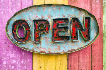 Old rustic 'OPEN' retro sign on a colorful painted fence