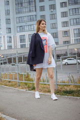 Fototapeta premium Beautiful woman with nude legs walking around city street wearing long white shirt
