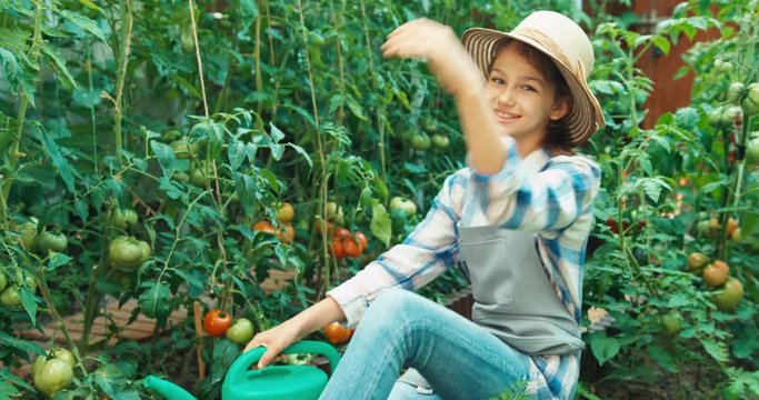 Girl watering her tomatoes in kitchen garden