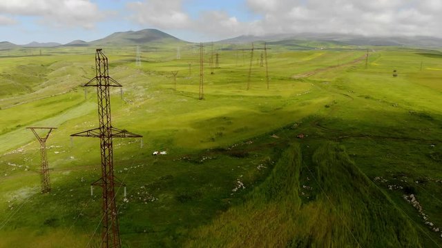 Aerial shot of the electricity pylons under puffy clouds