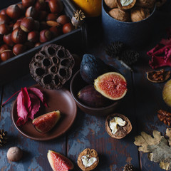 Fresh organic figs, nuts and autumn leaves on wooden board and dark stone table. Healthy lifestyle, seasonal fruit, sweet dessert, selective focus