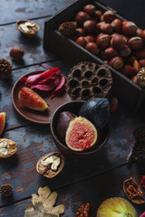 Obraz na płótnie Canvas Fresh organic figs, nuts and autumn leaves on wooden board and dark stone table. Healthy lifestyle, seasonal fruit, sweet dessert, selective focus