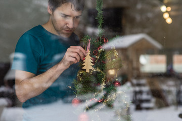Young man hanging wooden tree on a Christmas tree