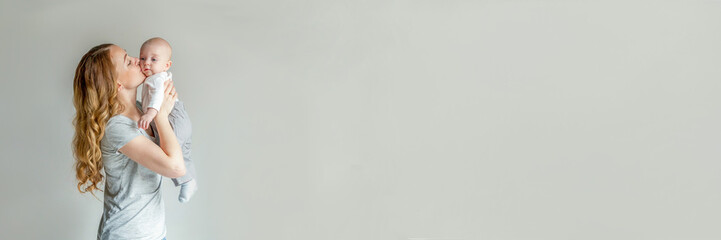 Mother holding her newborn child. Woman and infant boy relax and playing on white background. Mom of breast feeding baby. Family, maternity, tenderness, parenthood, responsibility concept. Banner