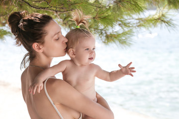 Mother and baby daughter on the beach having a great time together. Family vacation concept.