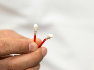 in the hands of a cotton swab and it is dirty, white background