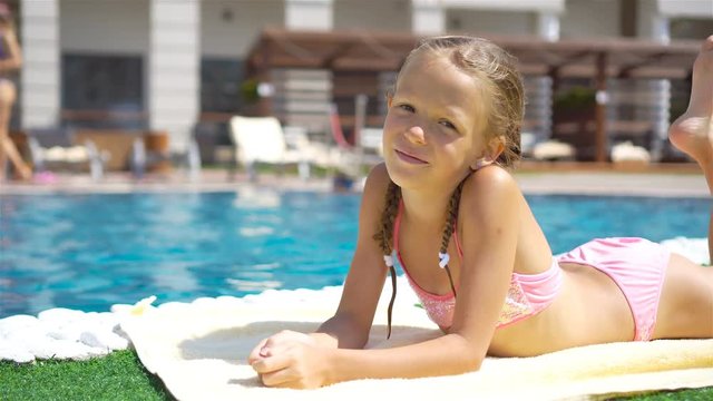 Beautiful little girl having fun near an outdoor pool
