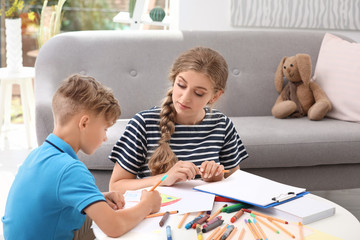 Young female psychologist working with little child in office