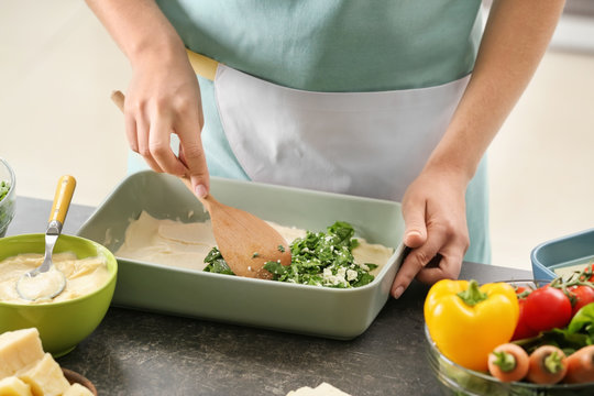 Woman cooking spinach lasagna in kitchen