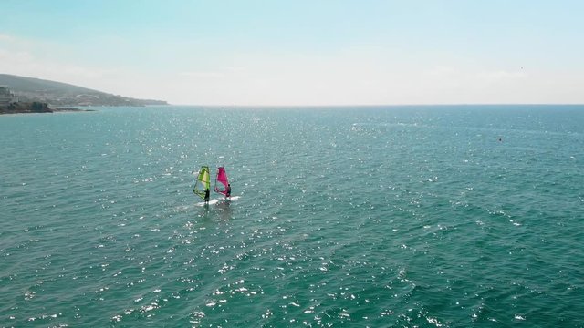 Cinematic aerial view of windsurfers sailing gliding across the sea extreme sport