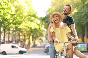 Happy couple riding bicycle together on street