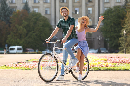 Happy couple riding bicycle together on street