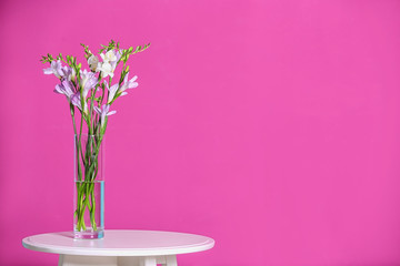 Beautiful fragrant freesia flowers in vase and space for text on color background
