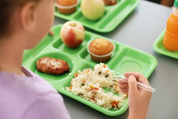 Girl sitting at table and eating healthy food during break at school, closeup