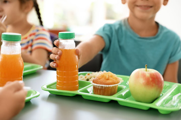 Children sitting at table and eating healthy food during break at school, closeup
