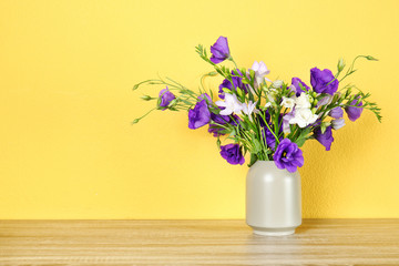 Vase with beautiful flowers on table against color background. Space for text
