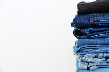 Stack of different jeans against white background. Space for text