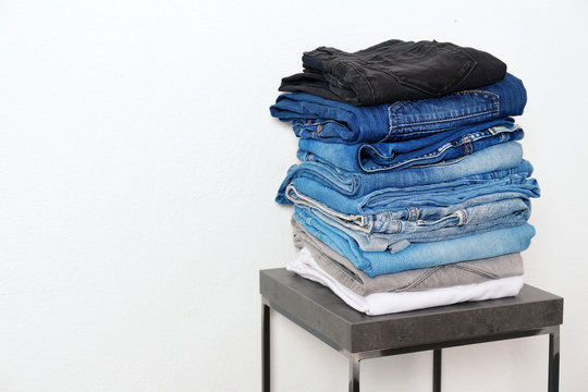 Stack of different jeans on table against white background. Space for text