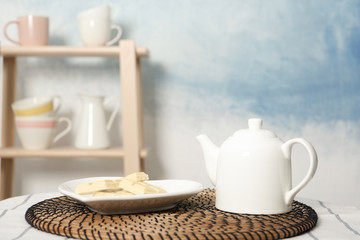 Tea pot and plate with white chocolate on table indoors