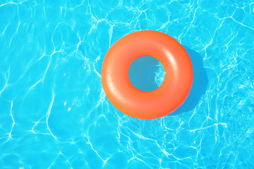 Inflatable ring floating in swimming pool on sunny day, top view