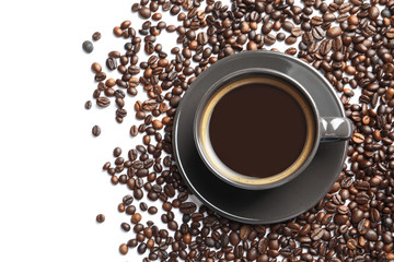 Roasted coffee beans and cup of hot beverage on white background, top view