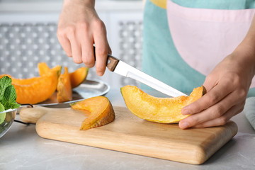 Obraz na płótnie Canvas Woman slicing fresh ripe melon on light table