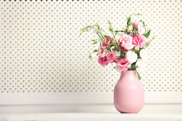 Vase with beautiful flowers on table against white wall, space for text