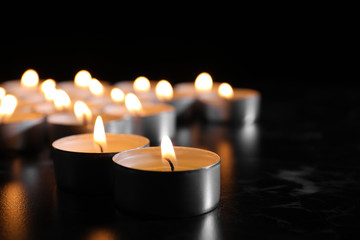 Burning candles on table in darkness, space for text. Funeral symbol
