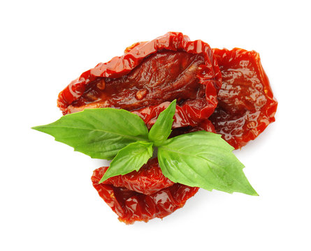 Tasty sun dried tomatoes with green leaves on white background