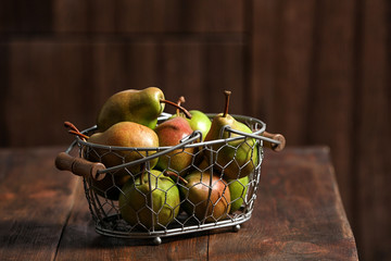 Basket with ripe pears on wooden table