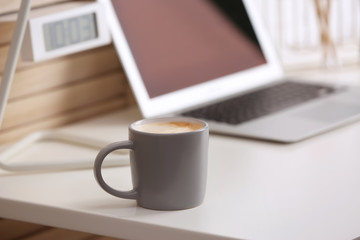 Coffee cup on table at modern workplace in office